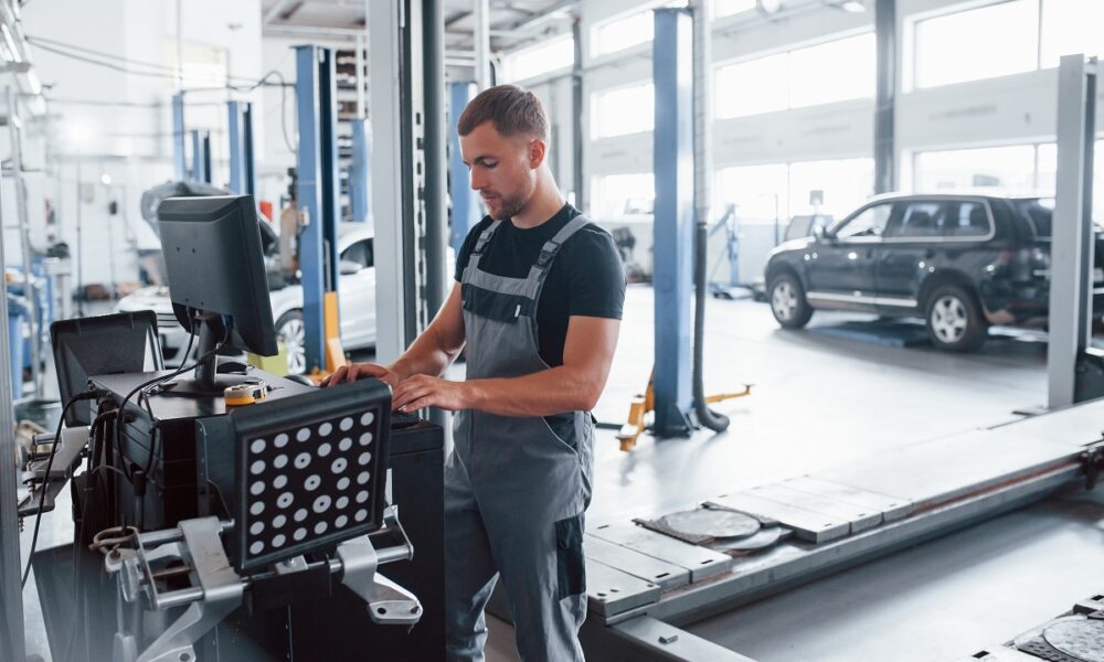 looks-at-keyboard-man-at-the-workshop-in-uniform-use-computer-for-his-job-for-fixing-broken-car